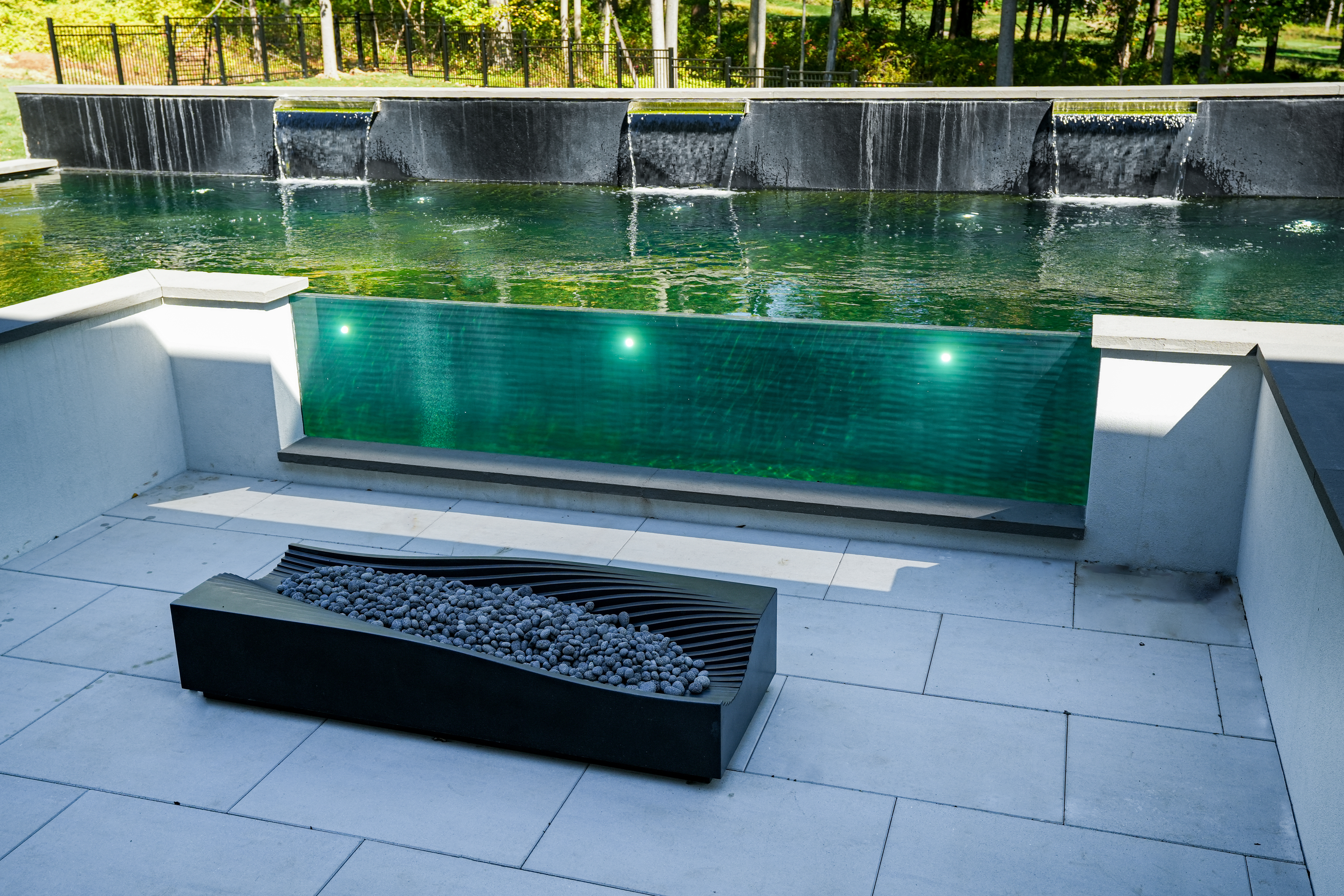 An additional 8-foot dripping water wall introduces another dimension of movement and sound, complementing the infinity edge while reinforcing the geometric lines of the surrounding architecture. An additional 8-foot dripping water wall introduces another dimension of movement and sound, complementing the infinity edge while reinforcing the geometric lines of the surrounding architecture.