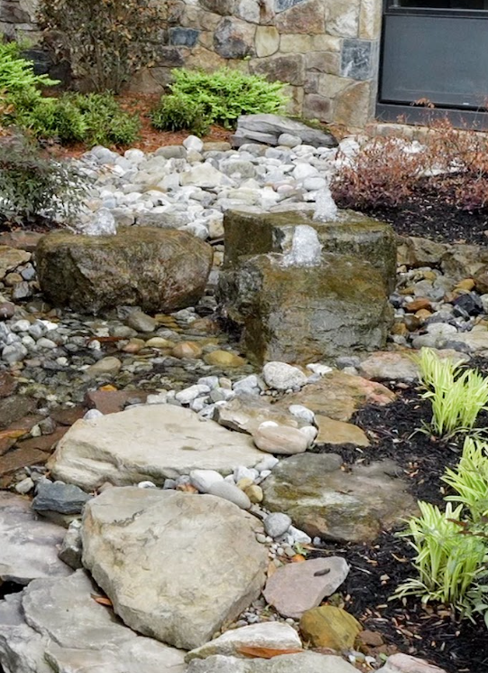 Near the front entrance, three large bubbling boulders emerge from the water.